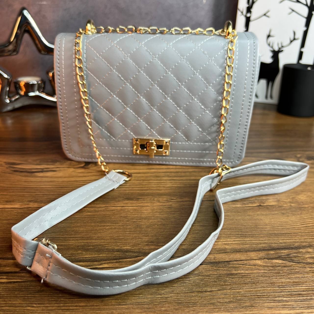 کیف دوشی زنانه طوسی رنگ با بند ترکیبی چرم و زنجیر طلایی، نمای نزدیک از قفل کیف.