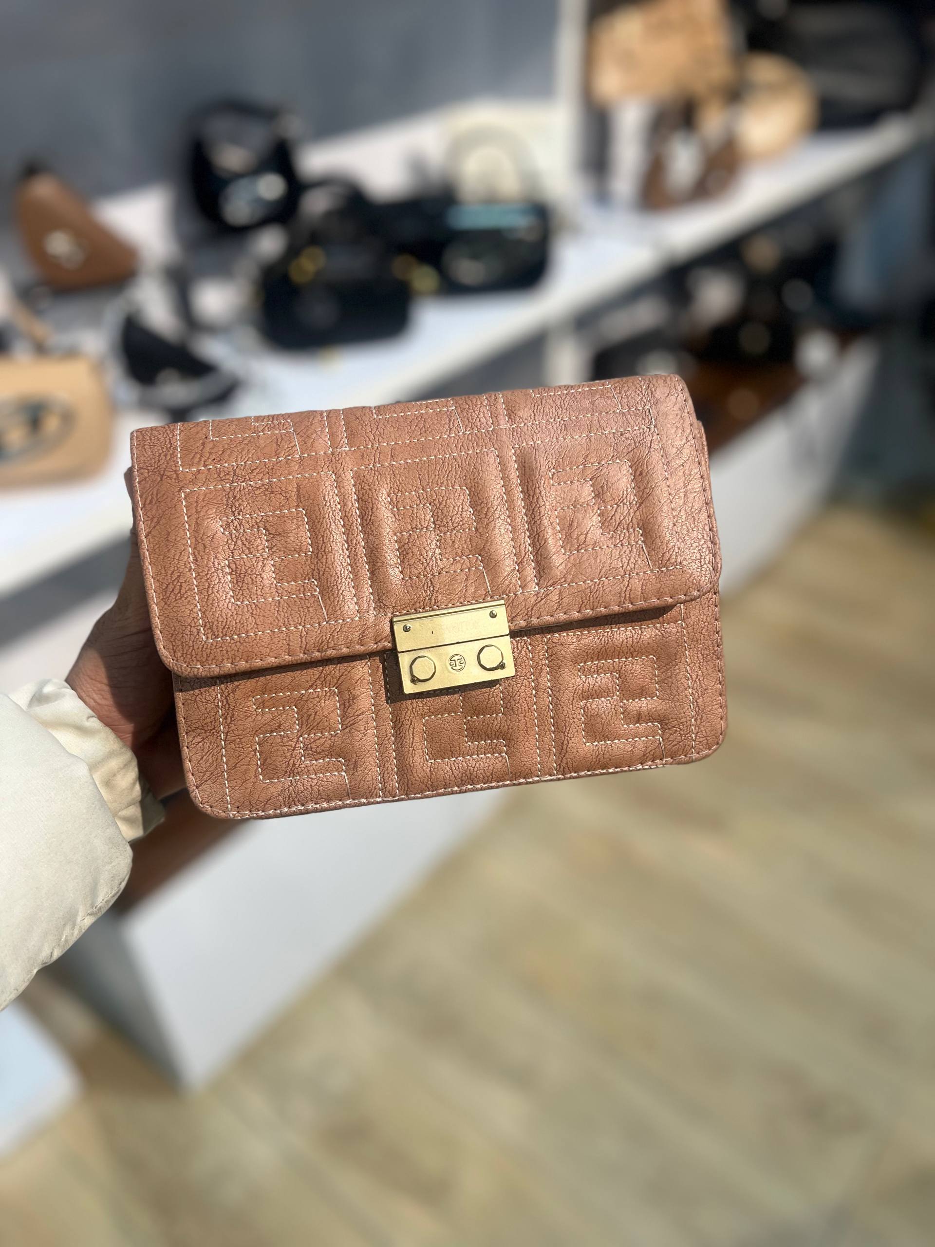 کیف دستی چرم دوکاره زنانه و مردانه به رنگ بژ هلویی روشن (Nude) با بافت لوزی، نمای نزدیک قفل طلایی، بدون بند.